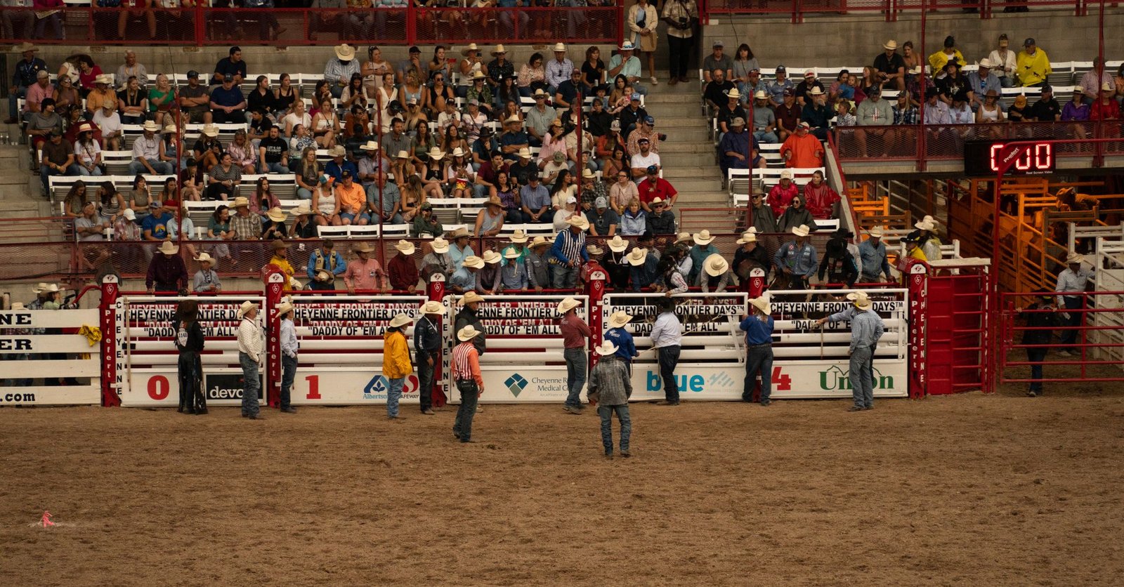 Arena de rodeio lotada com arquibancadas ao redor durante festa de peão